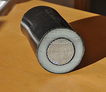 A high-voltage cable cross-section. The electrically conductive core is covered by a black protective layer, a white insulation layer of plastic and an additional black protective layer